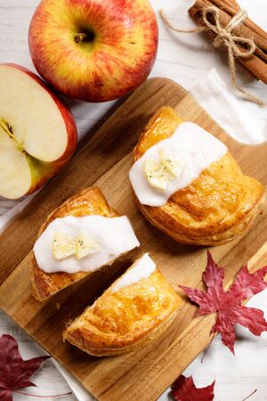 piece of cinnamon apple pie on a wooden board with fresh apple in background, autumn food conceptの写真素材
