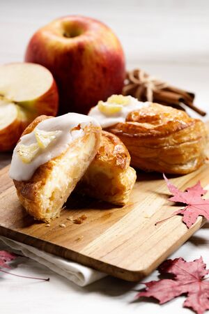 piece of cinnamon apple pie on a wooden board with fresh apple in background, autumn food conceptの写真素材