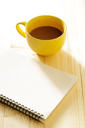 A cup of hot chocolate on wooden background with notebook.  Work from home concept.の写真素材