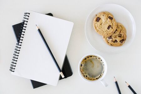A cup of hot black coffee on white table background with notebook and stationery.  Work from home concept.の写真素材