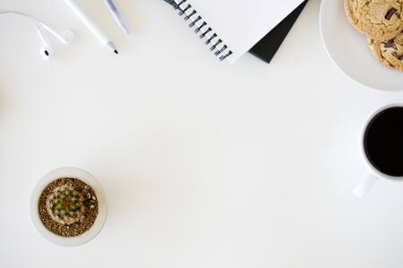 A cup of hot black coffee on white table background with notebook and stationery.  Work from home concept.の写真素材
