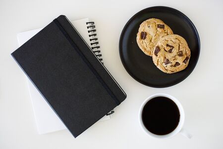 A cup of hot black coffee on white table background with notebook and stationery.  Work from home concept.の写真素材