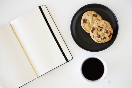 A cup of hot black coffee on white table background with notebook and stationery.  Work from home concept.の写真素材