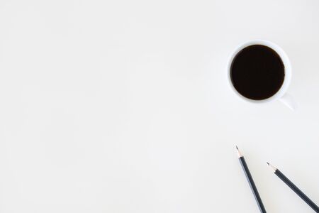 A cup of hot black coffee on white table background with notebook and stationery.  Work from home concept.の写真素材