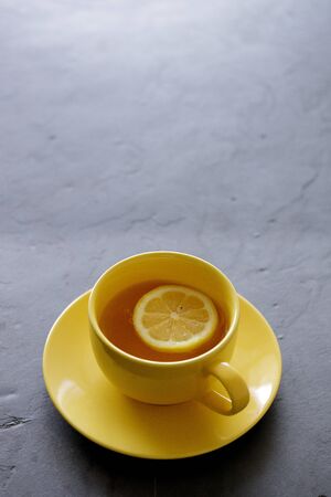 a cup of tea with fresh yellow lemons on black backgroundの写真素材