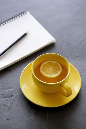 a cup of tea with fresh yellow lemons on black backgroundの写真素材
