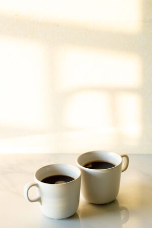 Two cups of coffees on white marble table in morning lightの写真素材
