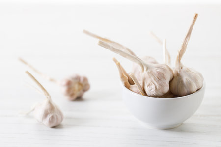 Ripe organic garlic clove and bulb on white wooden background.  Close-up. Selective focus.の写真素材