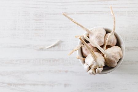 Ripe organic garlic clove and bulb on white wooden background.  Close-up. Selective focus.の写真素材