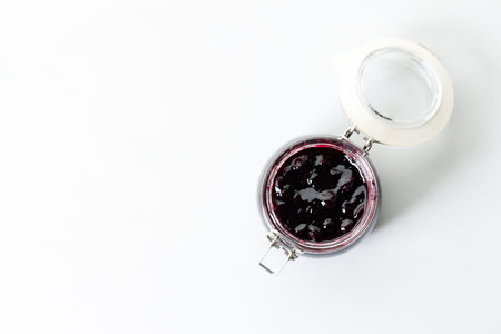 Jar of blueberry jam on white marble table background. Selective focus.