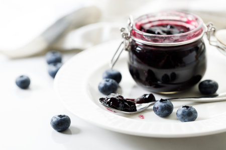 Blueberry jam with fresh berries on white marble table background. Selective focus.の写真素材