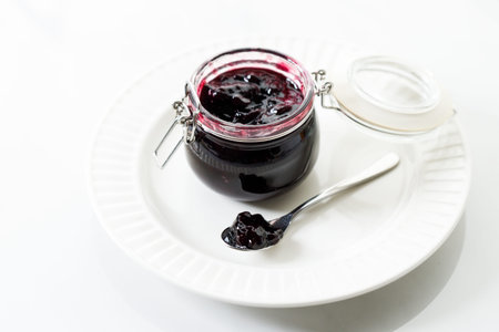 Jar of blueberry jam on white marble table background. Selective focus.