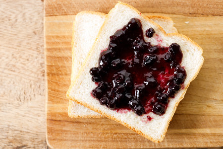Blueberry jam with fresh berries on bread on rustic wooden table background. Selective focus.の写真素材