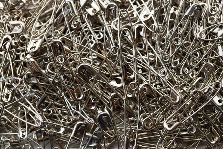 A number of stainless safety pins on white background.