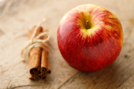 Ripe organic red apple and cinnamon stick on wooden table background.の写真素材