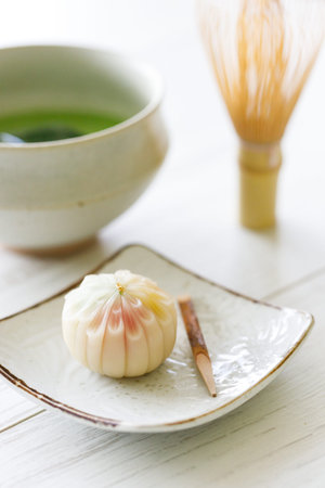 Cup of fresh matcha tea, green tea and Japanese confectionary on white wooden table.