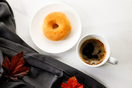 Cup of black coffee, Donut, leaves, on white marble background. Autumn composition. Copy space. Flat lay. Top view.の写真素材