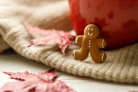 Gingerbread man and cup of delicious hot chocolate on warm sweater on white wooden table background. Selective focus. Copy space.の写真素材