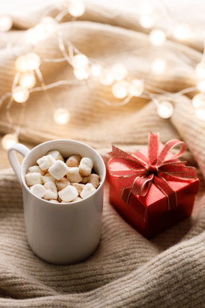 Cup of delicious hot chocolate and artisanal gift box tied with bows on warm sweater. Christmas New year concept. Selective focus.の写真素材