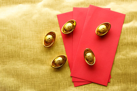 Red envelope and golden ingot or Yuanbao on golden color background for celebration happy Lunar New Year or Chinese New Year. Selective Focus. The letter means "Blessing"の写真素材