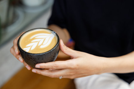 Cup of milk latte coffee hold in hands by the street. Selective focus.の写真素材