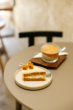 Cup of milk dirty coffee with a piece of cheese cake on table by the window. Selective focus.