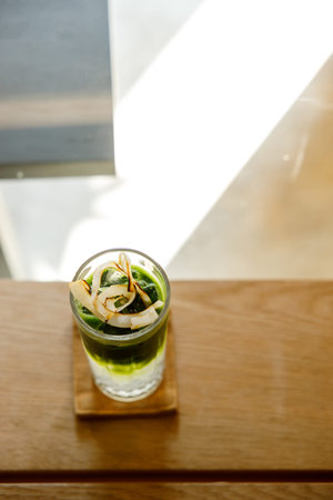 Glass of refreshing iced matcha tea with coconut water, green tea decorated with coconut meat...