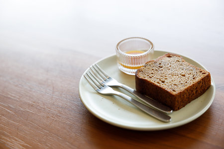 Moist Peanut butter Banana bread sliced with sauce on ceramic plate on wooden background. Selective...