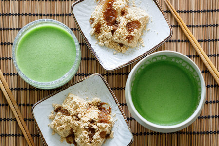 Cup of fresh matcha tea and Warabi mochi, traditional Japanese sweet from bracken starch on wooden...