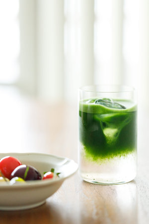 Cup of fresh matcha tea, green tea and colorful peach fruit shape Plating balls on wooden table....