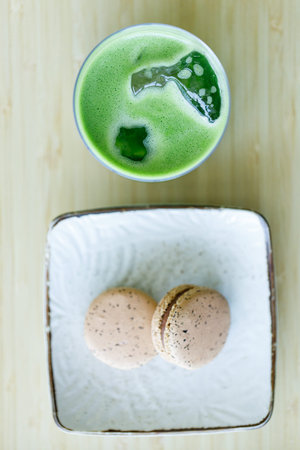 Glass of fresh matcha tea, green tea with coconut water and black tea flavor macaron,  on wooden...