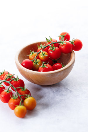 Fresh red cherry tomato in wooden bowl on white background. Selective focus.の写真素材