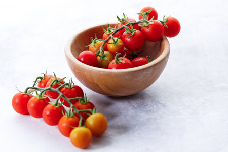 Fresh red cherry tomato in wooden bowl on white background. Selective focus.の写真素材