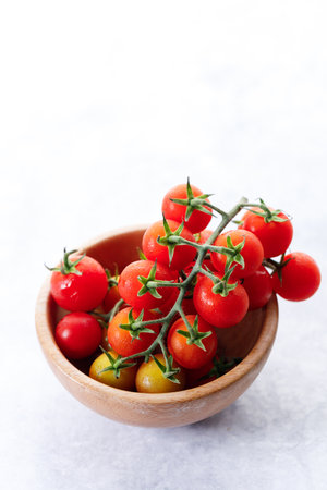 Fresh red cherry tomato in wooden bowl on white background. Selective focus.の写真素材