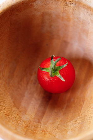 Fresh red cherry tomato on in wooden bowl. Selective focus.
