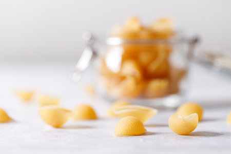 Raw uncooked dried Conchiglie shell pasta. Italian seashells pasta in jar on white background. Selective focusの写真素材