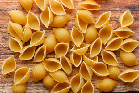 Raw uncooked dried Conchiglie shell pasta. Italian seashells pasta on wooden background. Selective focusの写真素材
