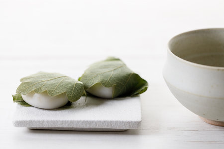 Kashiwa mochi and Cup of fresh matcha tea. Japanese sweet from mochi or rice cake and sweet red bean paste filling surrounded with Kashiwa or Oak leaf . Selective focus.の写真素材