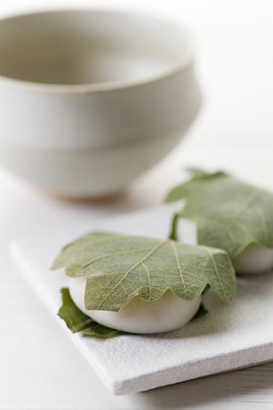 Kashiwa mochi and Cup of fresh matcha tea. Japanese sweet from mochi or rice cake and sweet red bean paste filling surrounded with Kashiwa or Oak leaf . Selective focus.の写真素材
