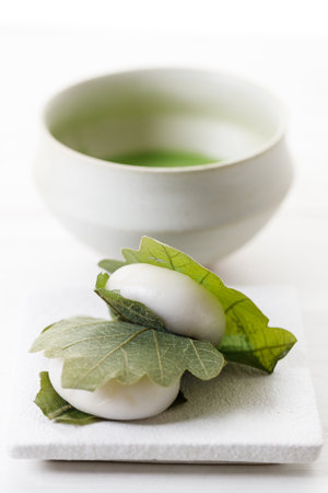 Kashiwa mochi and Cup of fresh matcha tea. Japanese sweet from mochi or rice cake and sweet red bean paste filling surrounded with Kashiwa or Oak leaf . Selective focus.の写真素材