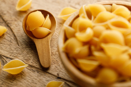 Raw uncooked dried Conchiglie shell pasta. Italian seashells pasta in wooden bowl on wooden background. Selective focusの写真素材
