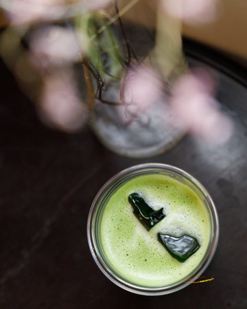 Top view of Cup of fresh matcha tea, green tea on wooden table with flower as foreground. Selective focus.の写真素材