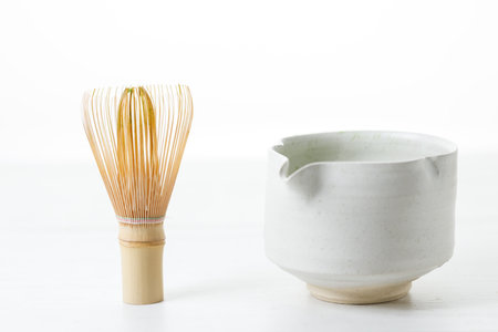 Cup of fresh matcha tea, green tea and Chasen, bamboo whisk, on white wooden table. Selective focus.の写真素材