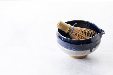 Japanese tea bowl glazed with blue and white color and Chasen or Bamboo whisk, an equipment for preparing matcha green tea on white wooden table. Selective focus.の写真素材
