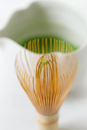 Cup of fresh matcha tea, green tea and Chasen, bamboo whisk, on white wooden table. Selective focus.の写真素材