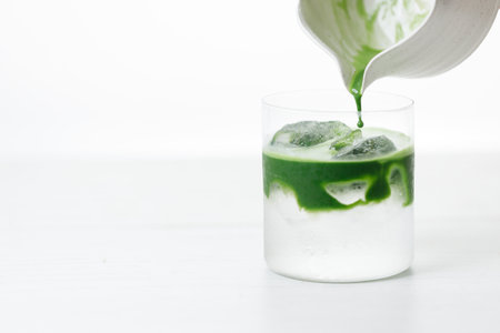 fresh matcha tea, green tea pouring on a glass of coconut water on white wooden table. Selective focus.の写真素材