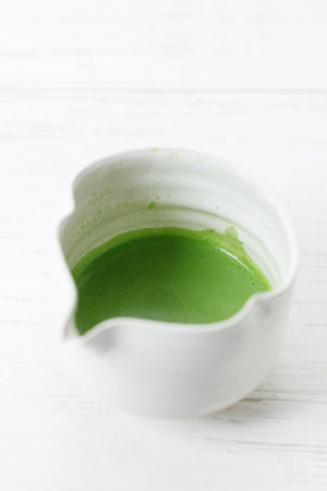 Cup of fresh matcha tea, green tea on white wooden table. Selective focus.の写真素材