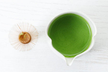 Cup of fresh matcha tea, green tea and Chasen, bamboo whisk, on white wooden table. Selective focus.の写真素材