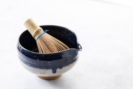 Japanese tea bowl glazed with blue and white color and Chasen or Bamboo whisk, an equipment for preparing matcha green tea on white wooden table. Selective focus.の写真素材