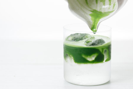 fresh matcha tea, green tea pouring on a glass of coconut water on white wooden table. Selective focus.の写真素材